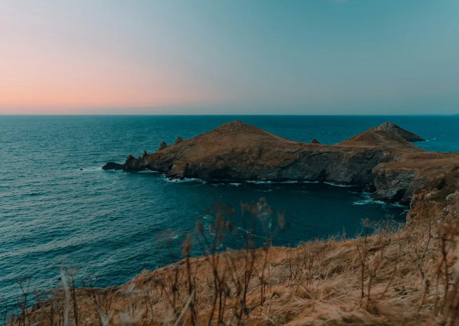 Pointe rocheuse sur une mer calme à l'heure bleue